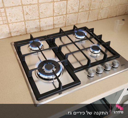 כיריים גז עם להבות כחולות על משטח מטבח
